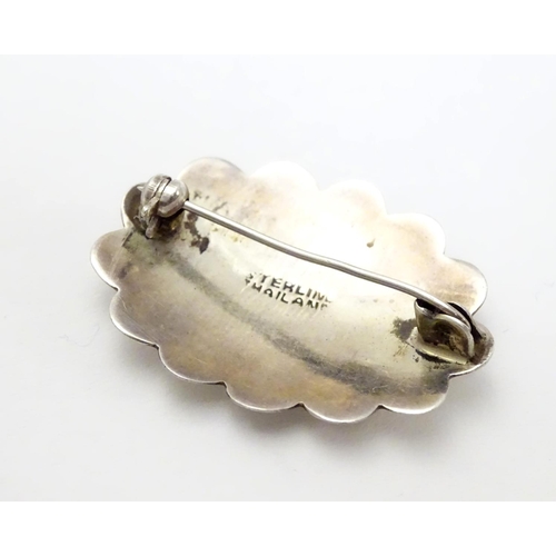 504 - A silver brooch of scalloped oval form with engraved decoration, marked Sterling Thailand. 1 1/4