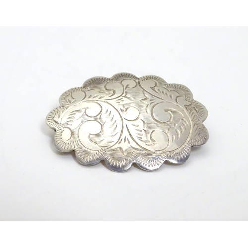 504 - A silver brooch of scalloped oval form with engraved decoration, marked Sterling Thailand. 1 1/4