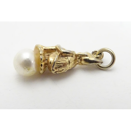 511 - A gilt metal novelty pendant/ charm formed as a pixie / imp  sat on a pearl. Approx 3 1/4