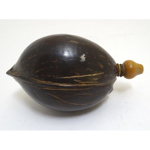 923 - A 19thC carved coconut 'bugbear' Napoleonic flask, with a turned boxwood spout, carved with gothic i... 