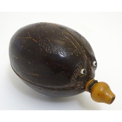 923 - A 19thC carved coconut 'bugbear' Napoleonic flask, with a turned boxwood spout, carved with gothic i... 