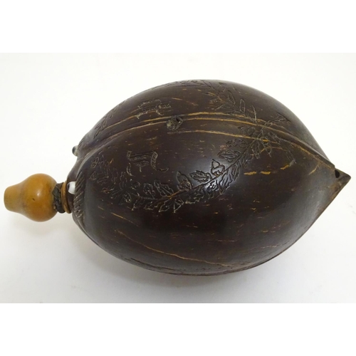 923 - A 19thC carved coconut 'bugbear' Napoleonic flask, with a turned boxwood spout, carved with gothic i... 