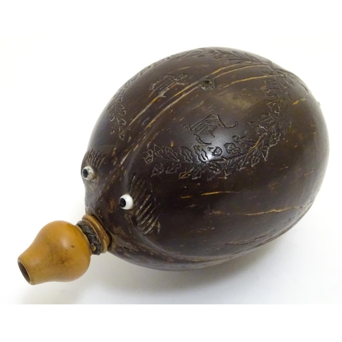 923 - A 19thC carved coconut 'bugbear' Napoleonic flask, with a turned boxwood spout, carved with gothic i... 