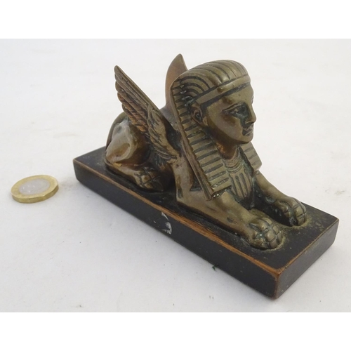 969 - A 20thC paperweight formed as a winged sphinx with the head of a pharaoh on a rectangular wooden bas... 