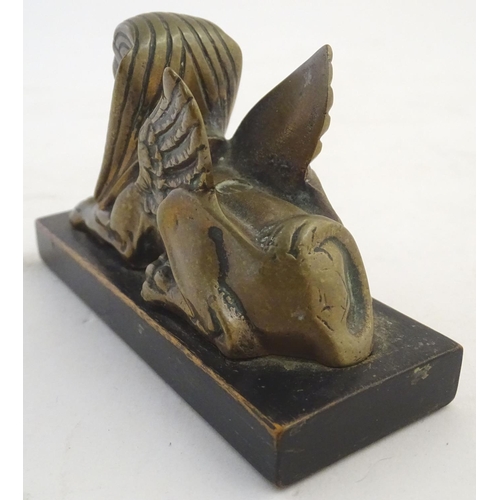 969 - A 20thC paperweight formed as a winged sphinx with the head of a pharaoh on a rectangular wooden bas... 