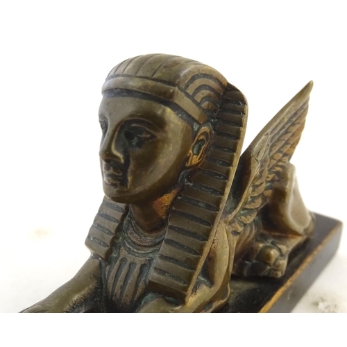 969 - A 20thC paperweight formed as a winged sphinx with the head of a pharaoh on a rectangular wooden bas... 