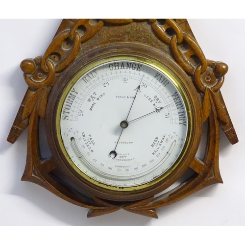 1196 - A Victorian aneroid barometer by Field & Son, Aylesbury, the carved oak case decorated with naval mo... 