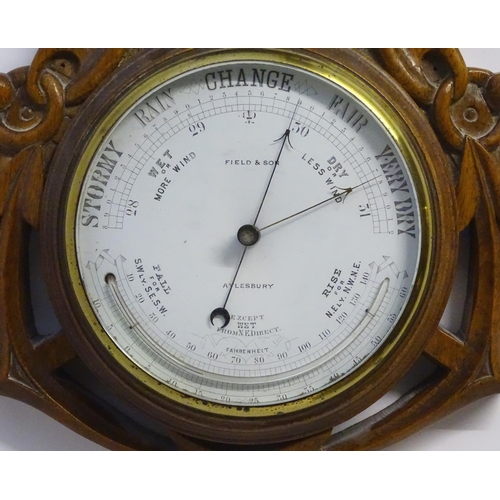 1196 - A Victorian aneroid barometer by Field & Son, Aylesbury, the carved oak case decorated with naval mo... 