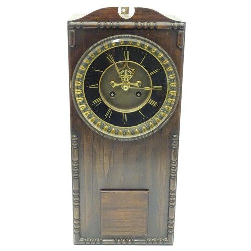 1197A - An Edwardian wall clock, the stained oak case housing a black and gilt numeral dial, 17 3/4