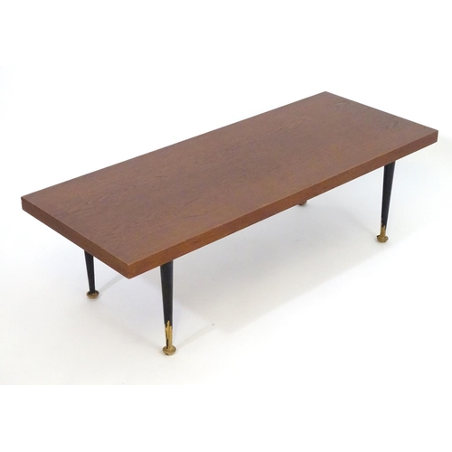 1233 - A mid 20thC Meredew coffee table with a rectangular teak top above four turned tapering legs. Bearin... 