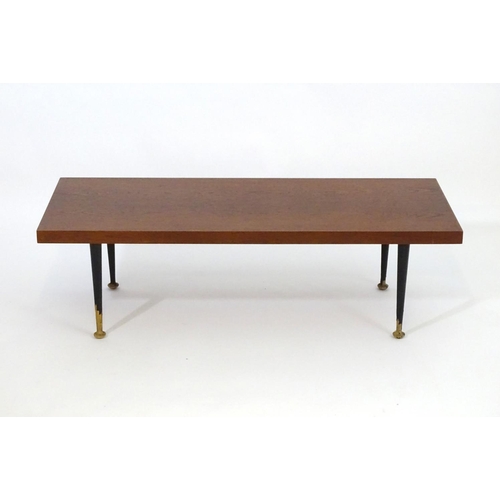 1233 - A mid 20thC Meredew coffee table with a rectangular teak top above four turned tapering legs. Bearin... 