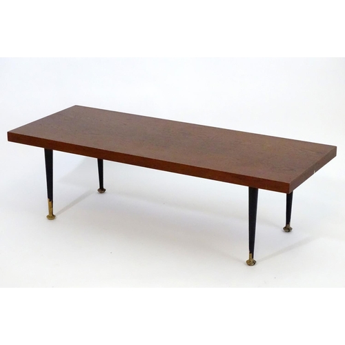 1233 - A mid 20thC Meredew coffee table with a rectangular teak top above four turned tapering legs. Bearin... 