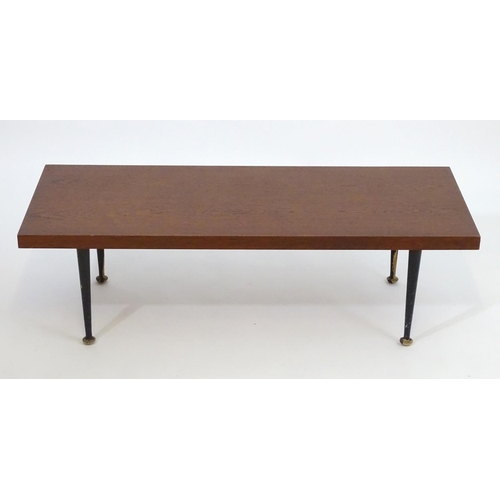 1233 - A mid 20thC Meredew coffee table with a rectangular teak top above four turned tapering legs. Bearin... 