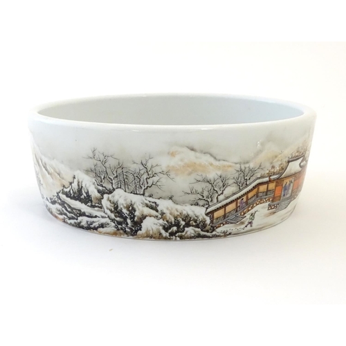 26 - A Chinese circular dish with hand painted decoration depicting a winter snowy landscape scene with m... 