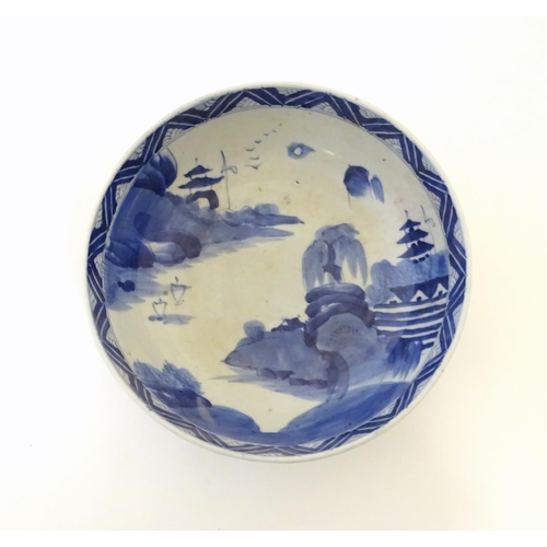 9 - A Chinese blue and white bowl with hand painted decoration depicting an Oriental landscape with pago... 