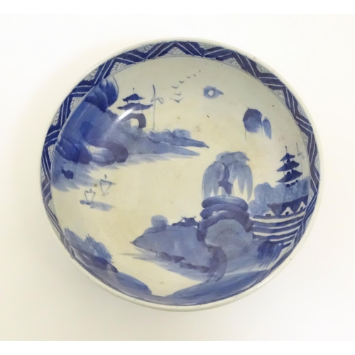 9 - A Chinese blue and white bowl with hand painted decoration depicting an Oriental landscape with pago... 