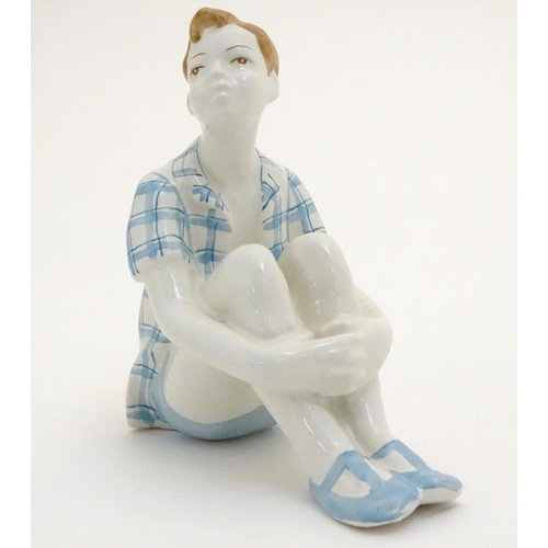 85 - A Russian figure modelled as a seated boy / dreamer. Marked under. Approx. 4 1/2