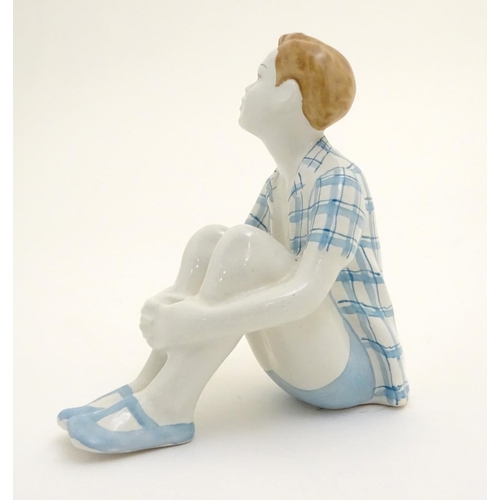 85 - A Russian figure modelled as a seated boy / dreamer. Marked under. Approx. 4 1/2