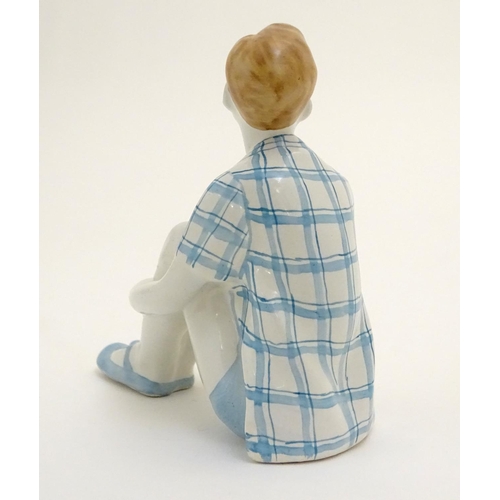 85 - A Russian figure modelled as a seated boy / dreamer. Marked under. Approx. 4 1/2