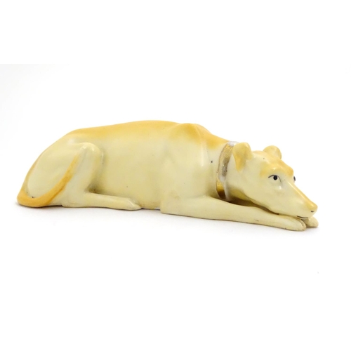 88 - A 20thC porcelain model of a recumbent greyhound dog with a gilt collar. Approx. 8 1/4