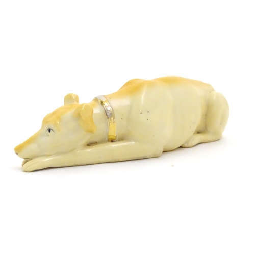 88 - A 20thC porcelain model of a recumbent greyhound dog with a gilt collar. Approx. 8 1/4