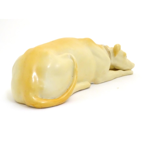 88 - A 20thC porcelain model of a recumbent greyhound dog with a gilt collar. Approx. 8 1/4