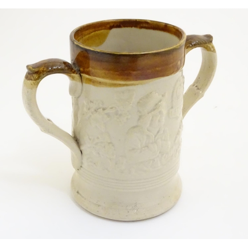 94 - A 19thC two tone stoneware loving cup tankard, the body moulded in relief with tavern scenes with Im... 