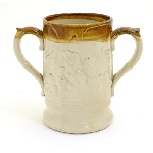 94 - A 19thC two tone stoneware loving cup tankard, the body moulded in relief with tavern scenes with Im... 