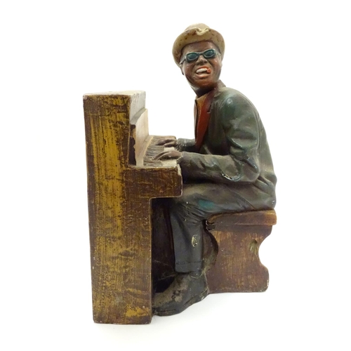 1013 - A 20thC model of a black gentleman playing the piano, possibly Ray Charles. Approx. 15 1/2