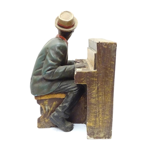 1013 - A 20thC model of a black gentleman playing the piano, possibly Ray Charles. Approx. 15 1/2