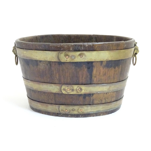 1025 - A 19thC coopered oak and brass banded ice bucket / wine cooler with twin lion mask ring handles. App... 