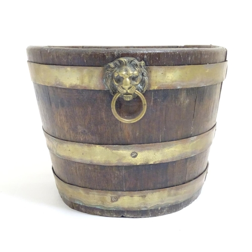 1025 - A 19thC coopered oak and brass banded ice bucket / wine cooler with twin lion mask ring handles. App... 