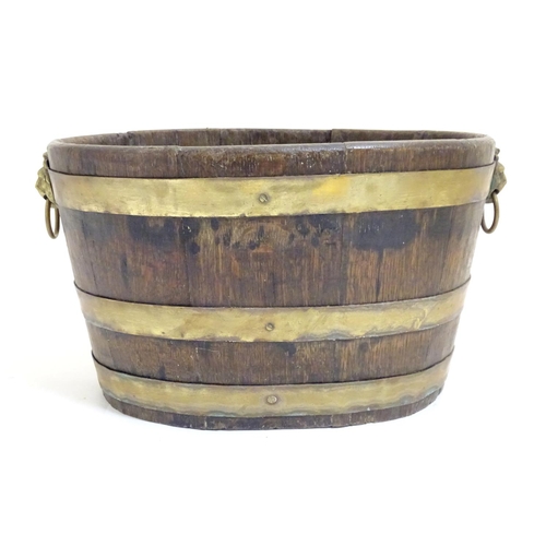 1025 - A 19thC coopered oak and brass banded ice bucket / wine cooler with twin lion mask ring handles. App... 