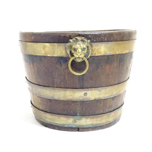 1025 - A 19thC coopered oak and brass banded ice bucket / wine cooler with twin lion mask ring handles. App... 