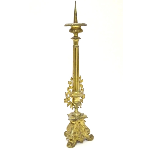 1031 - A 20thC large ecclesiastical gilded pricket candlestick with a fluted column flanked by applied vine... 