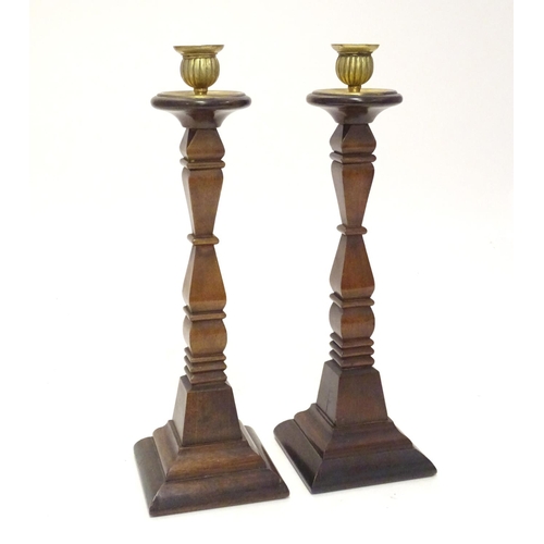 1054 - A pair of early 20thC carved wooden candlesticks of squared form with brass sconces. Approx. 14