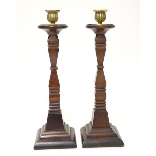 1054 - A pair of early 20thC carved wooden candlesticks of squared form with brass sconces. Approx. 14