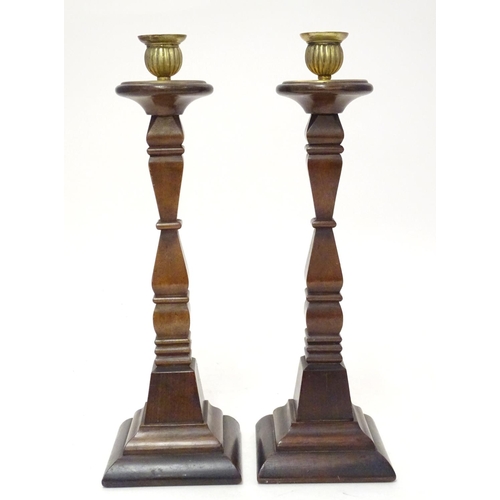 1054 - A pair of early 20thC carved wooden candlesticks of squared form with brass sconces. Approx. 14