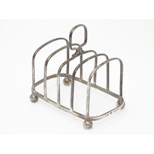 196 - A Silver four division toast rack raised on four bun feet. Hallmarked Birmingham 1923 maker Haseler ... 