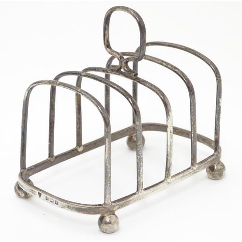 196 - A Silver four division toast rack raised on four bun feet. Hallmarked Birmingham 1923 maker Haseler ... 