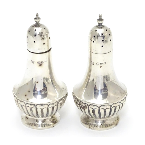 300 - A pair of silver pepperettes with fluted decoration. Hallmarked Chester 1900, maker Colen Hewer Ches... 