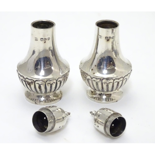 300 - A pair of silver pepperettes with fluted decoration. Hallmarked Chester 1900, maker Colen Hewer Ches... 