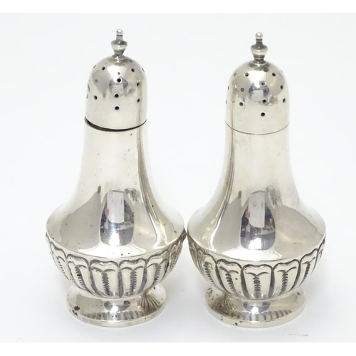 300 - A pair of silver pepperettes with fluted decoration. Hallmarked Chester 1900, maker Colen Hewer Ches... 