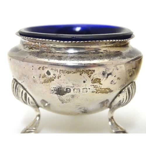 312 - A pair of circular silver table salts, each raised on three hoof feet, with blue glass liners and ma... 