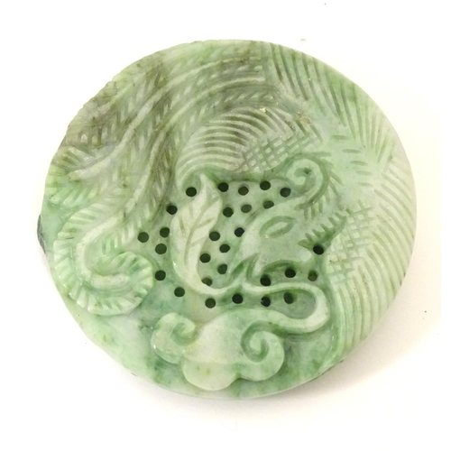 846 - An Oriental jade roundel carving depicting a stylised dragon. Approx. 2 1/4