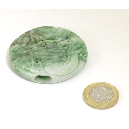 846 - An Oriental jade roundel carving depicting a stylised dragon. Approx. 2 1/4