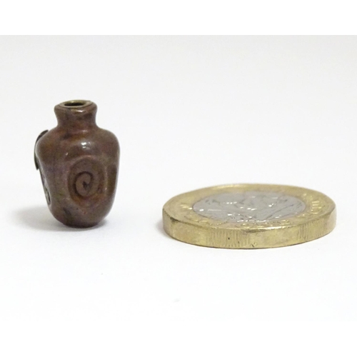 865 - A Japanese ojime bead formed as a stylised vase with impressed detail and applied brass character ma... 