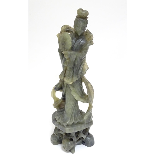 867 - An Oriental carved soapstone figure of a lady holding a fan, wearing flowing robes, on a carved base... 