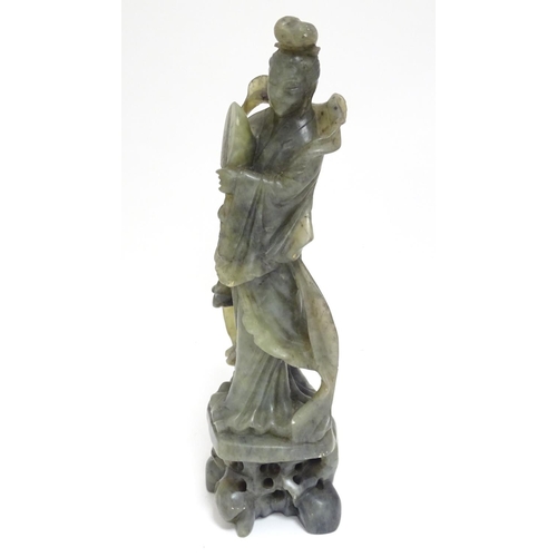 867 - An Oriental carved soapstone figure of a lady holding a fan, wearing flowing robes, on a carved base... 