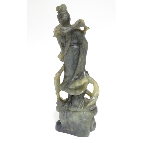 867 - An Oriental carved soapstone figure of a lady holding a fan, wearing flowing robes, on a carved base... 